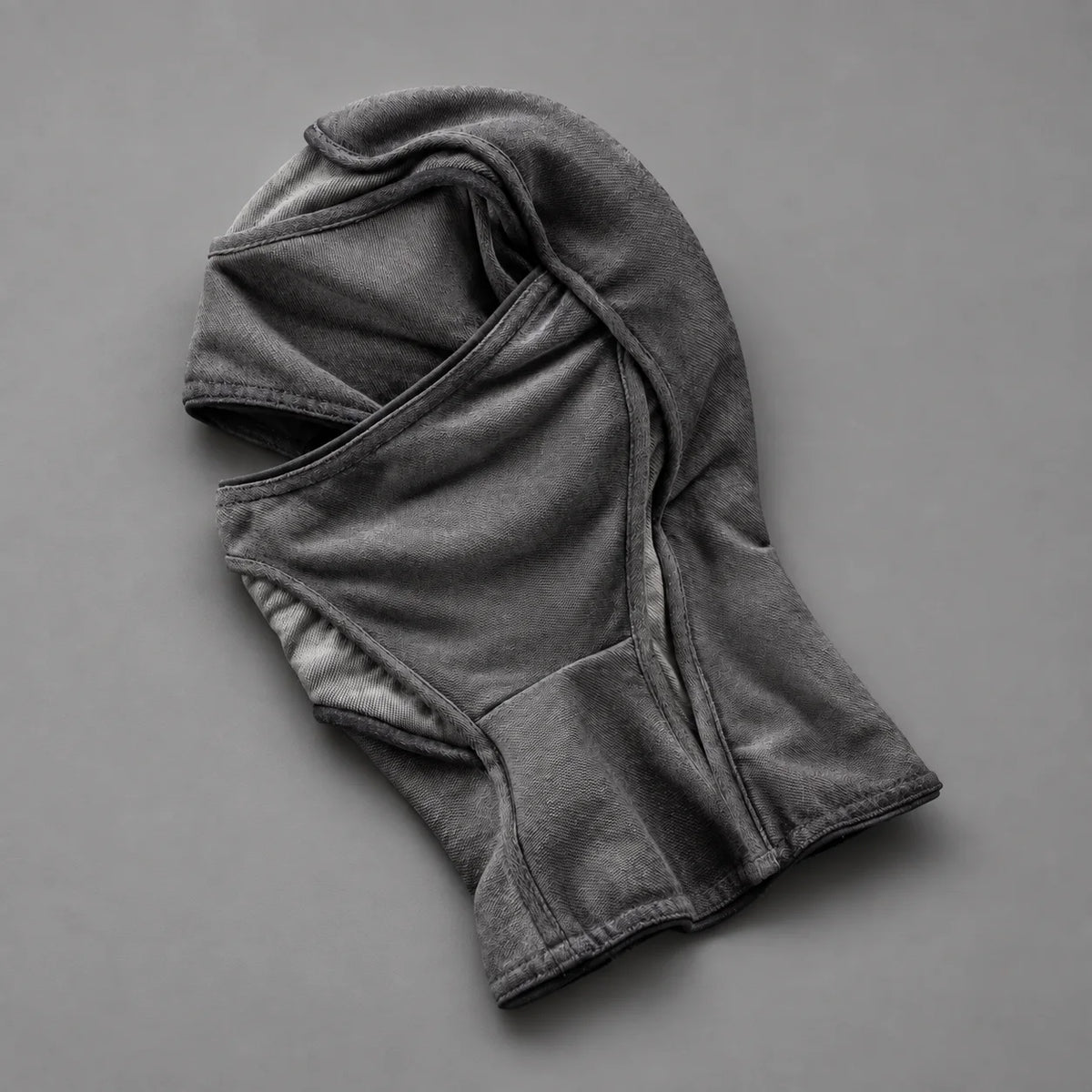 Grey Deamon facemask laid flat, showing the eye opening and curved fabric panels